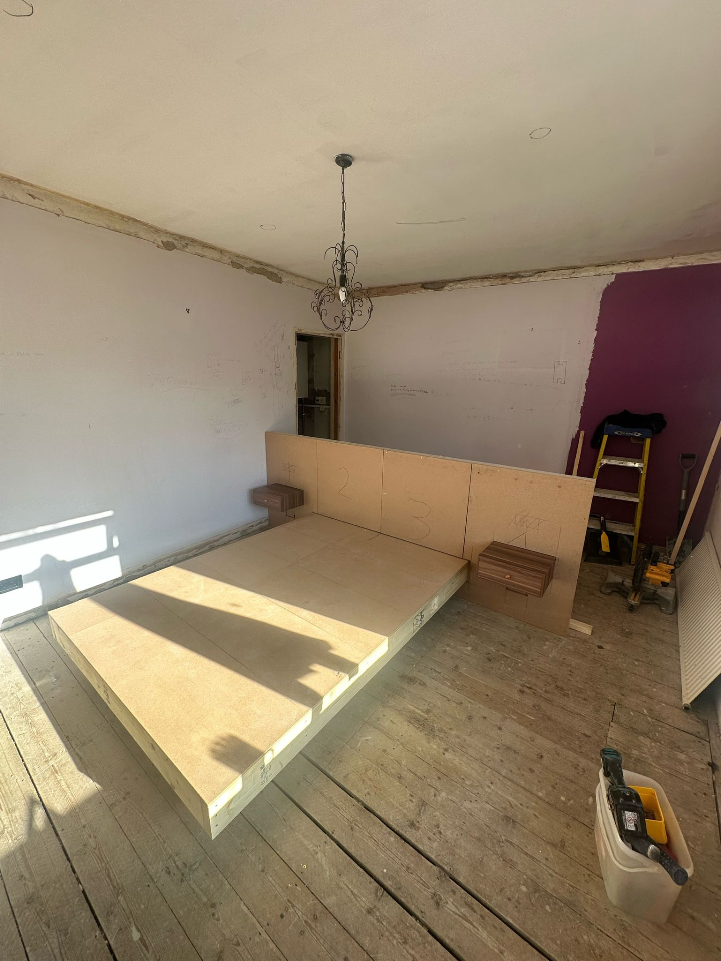 Floating bed platform boarded out with bedside tables set in
