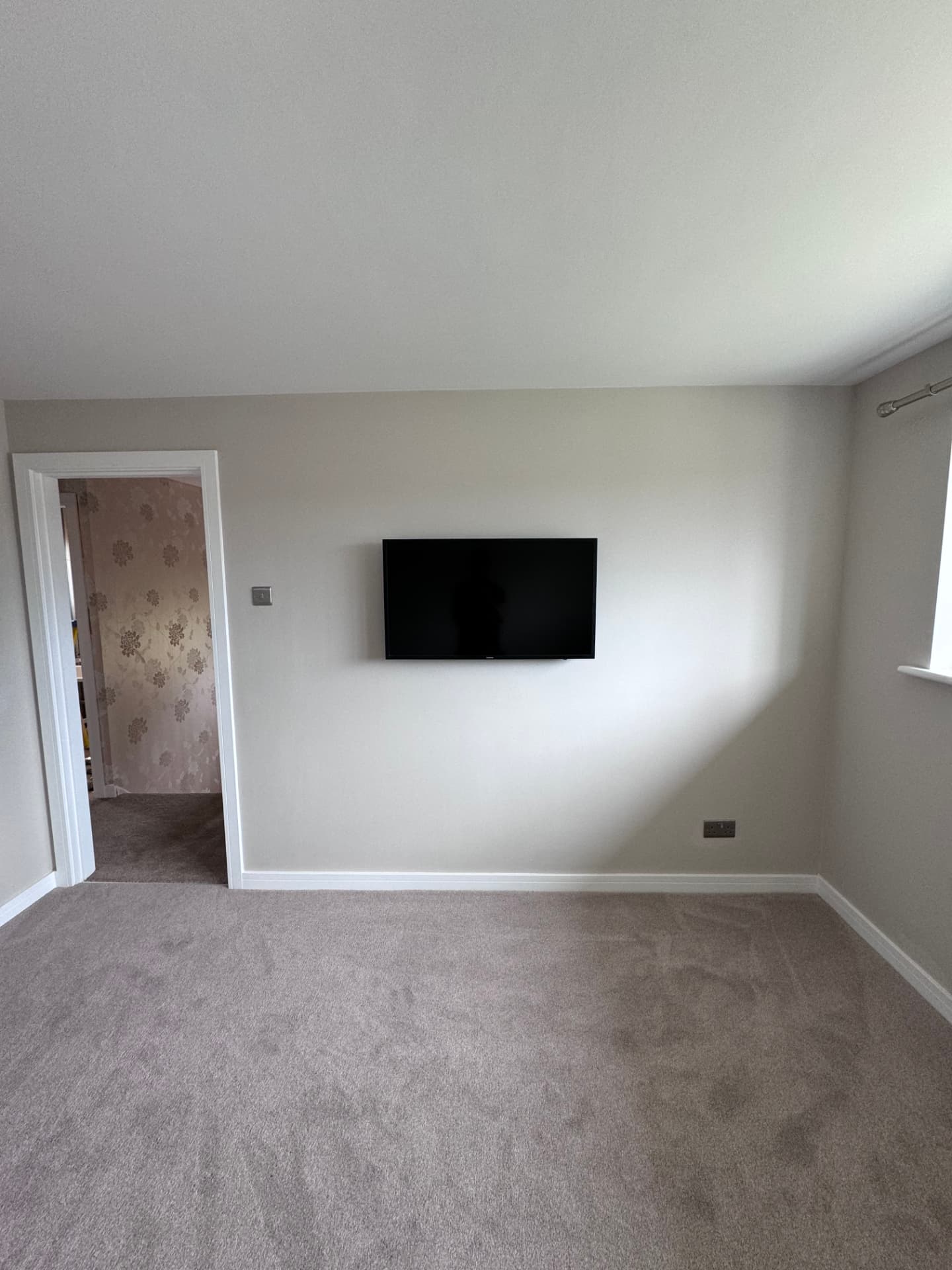 Redecorated bedroom with new carpet and wall-mounted TV