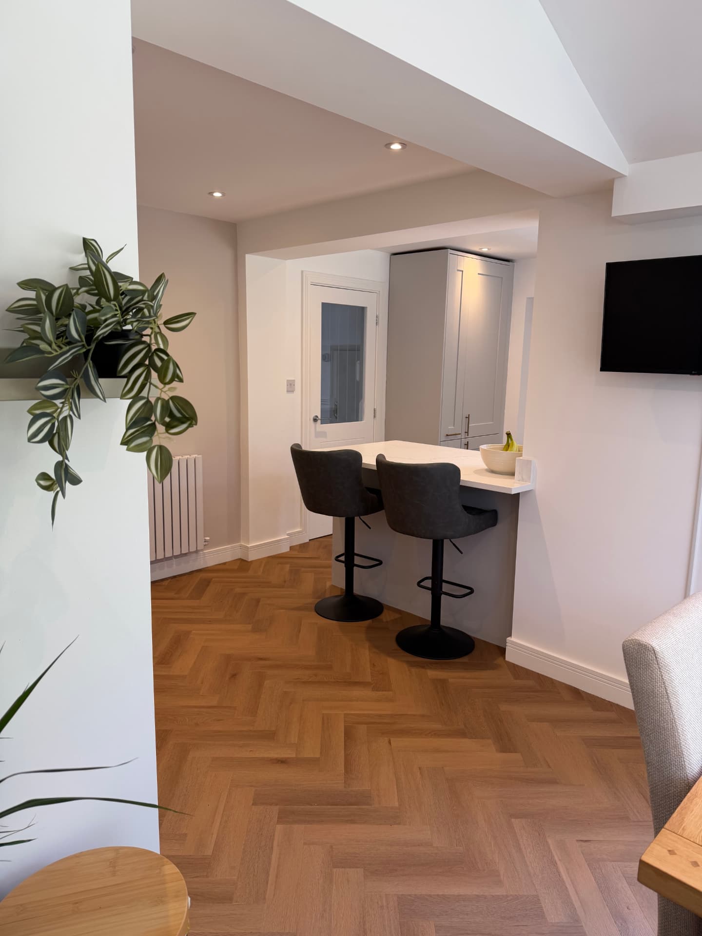 Open-plan view across the herringbone floor to the breakfast bar