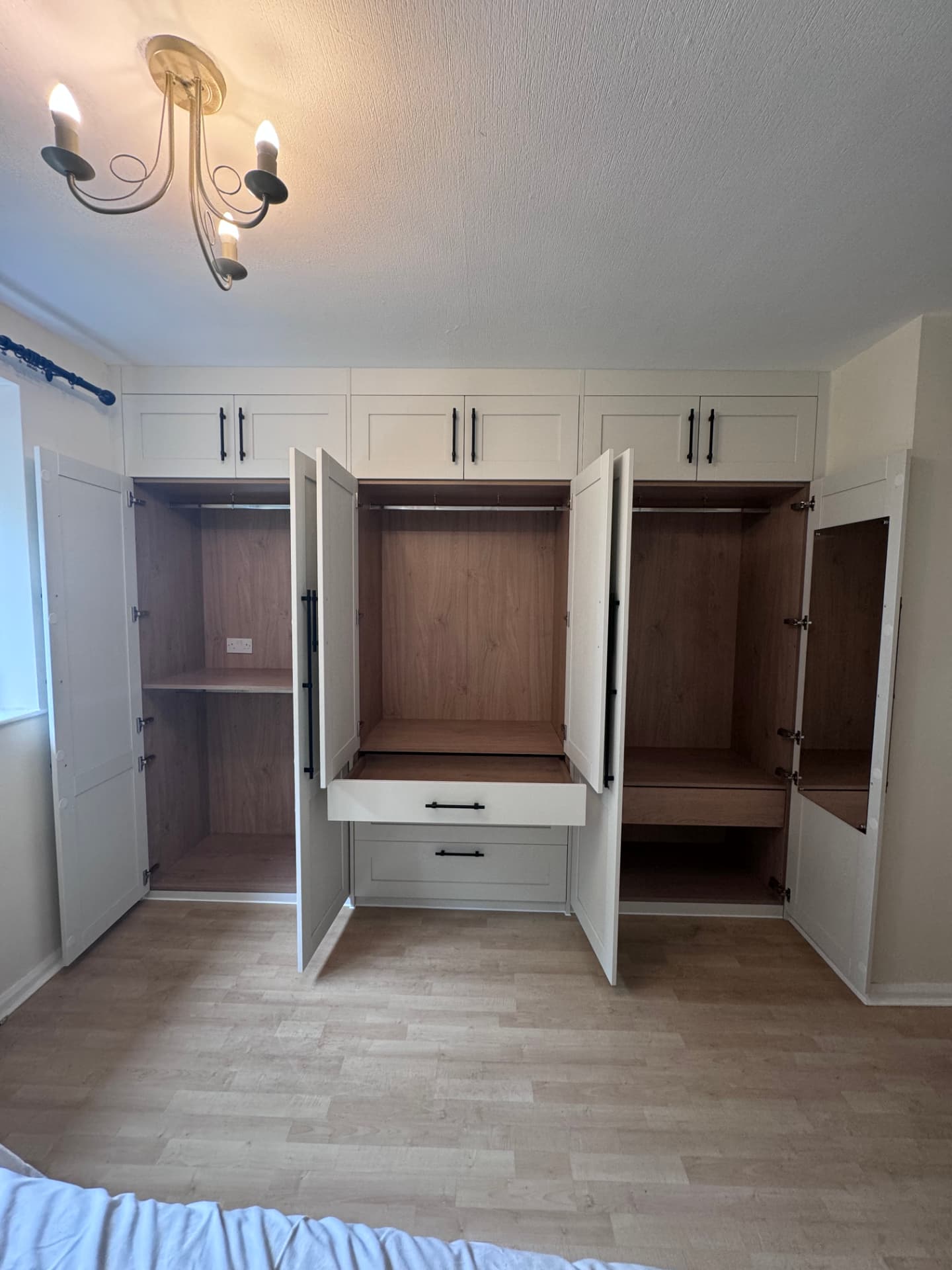 Fitted wardrobes open showing oak interiors, hanging rails and drawers