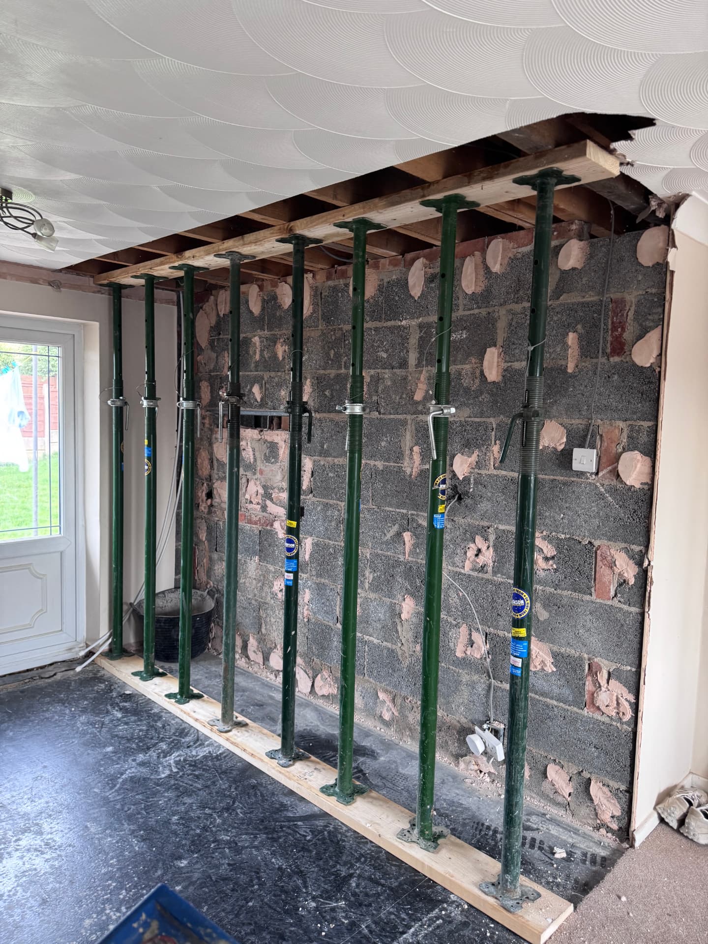 Acrow props supporting the ceiling with the wall hacked back to blockwork