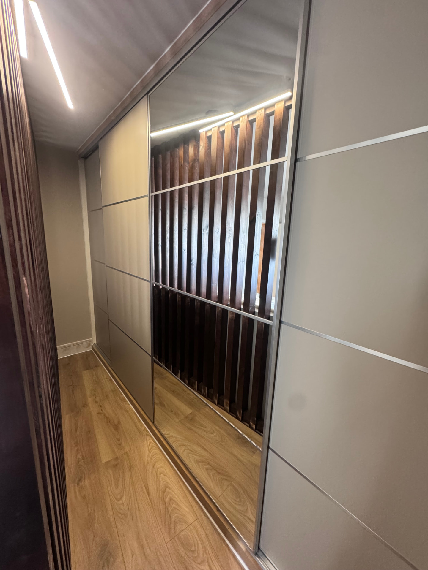 Finished walk-in wardrobe with mirrored sliding doors and LED lighting