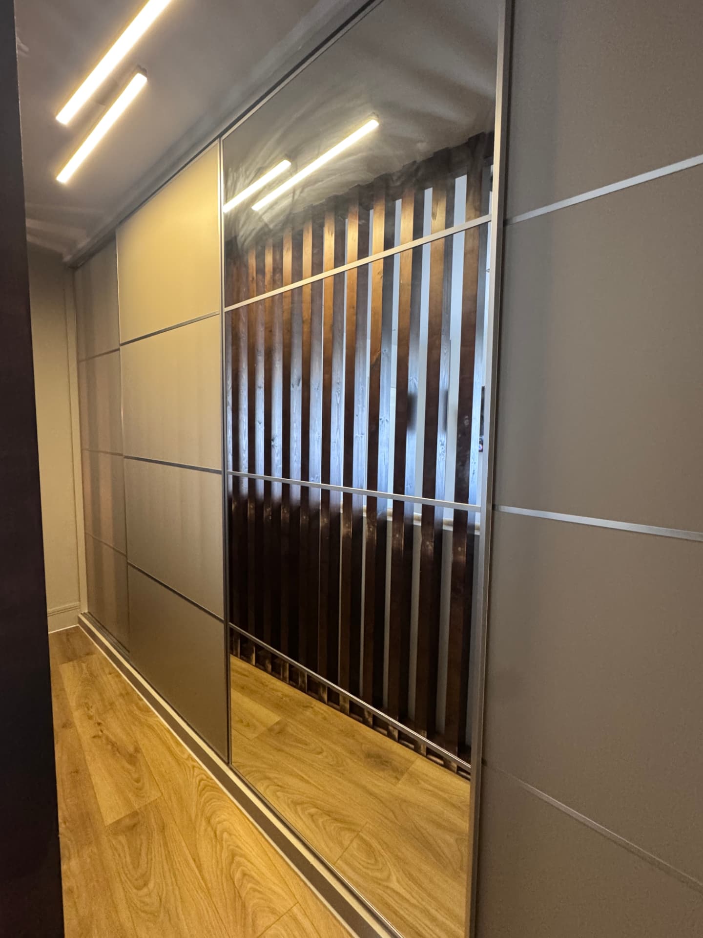 Sliding mirrored wardrobe doors fitted along a bedroom wall