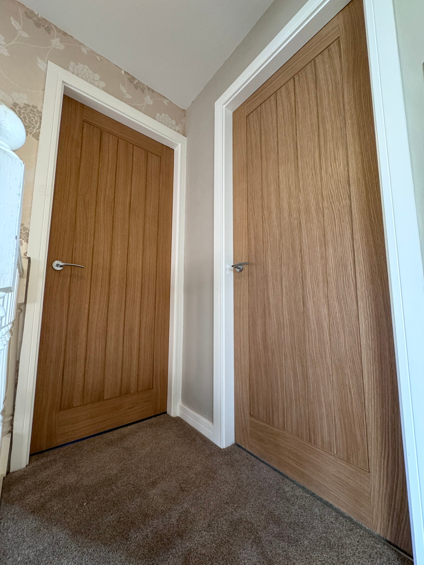 Two oak internal doors fitted in a hallway with white architraves