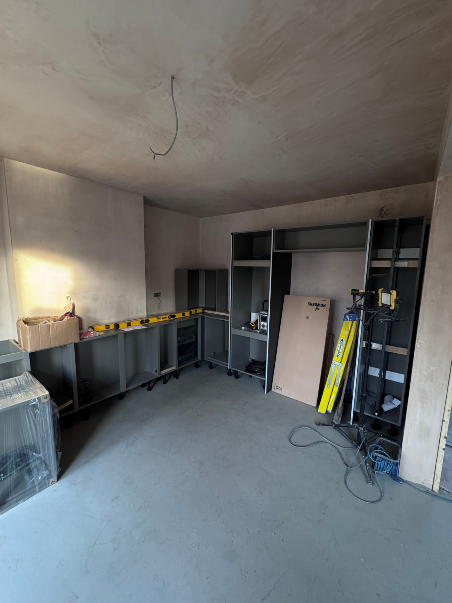 Howdens kitchen carcasses being set out on freshly plastered walls