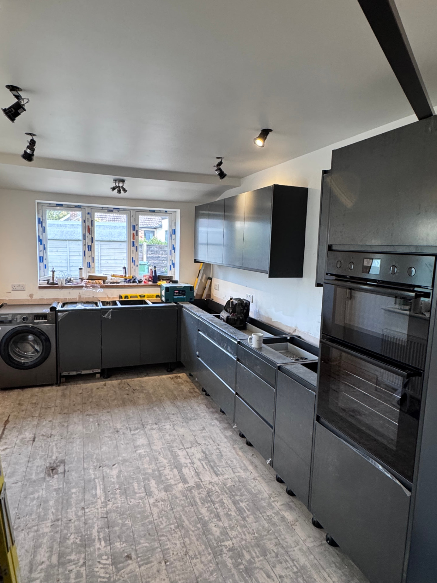Graphite kitchen units being installed with double oven in place