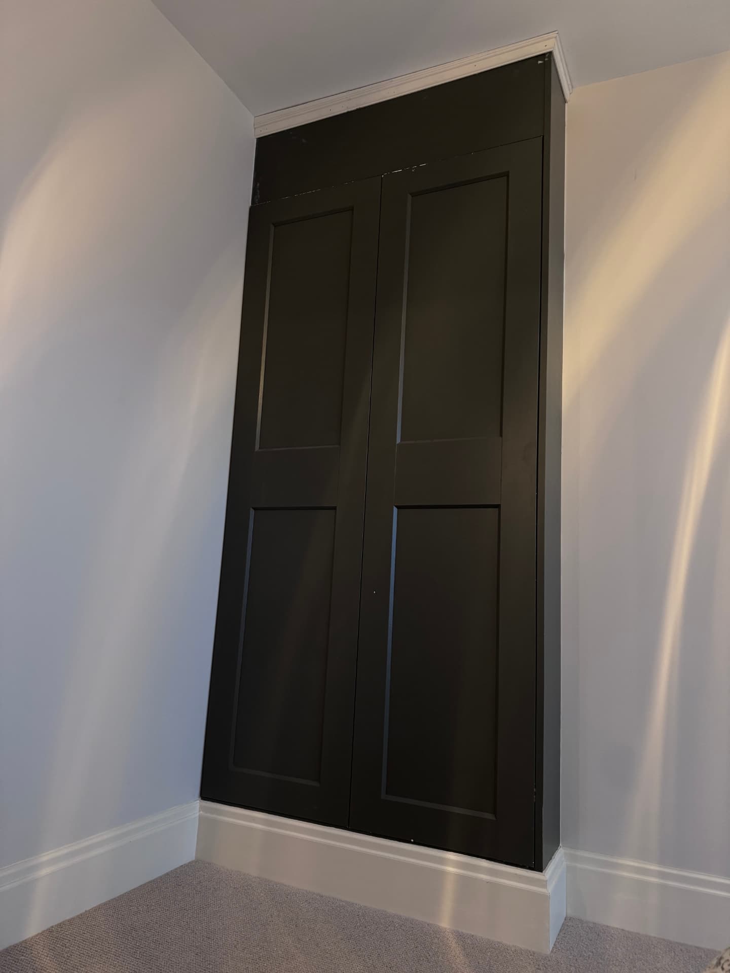 Black painted alcove cupboard with panelled doors and cornice