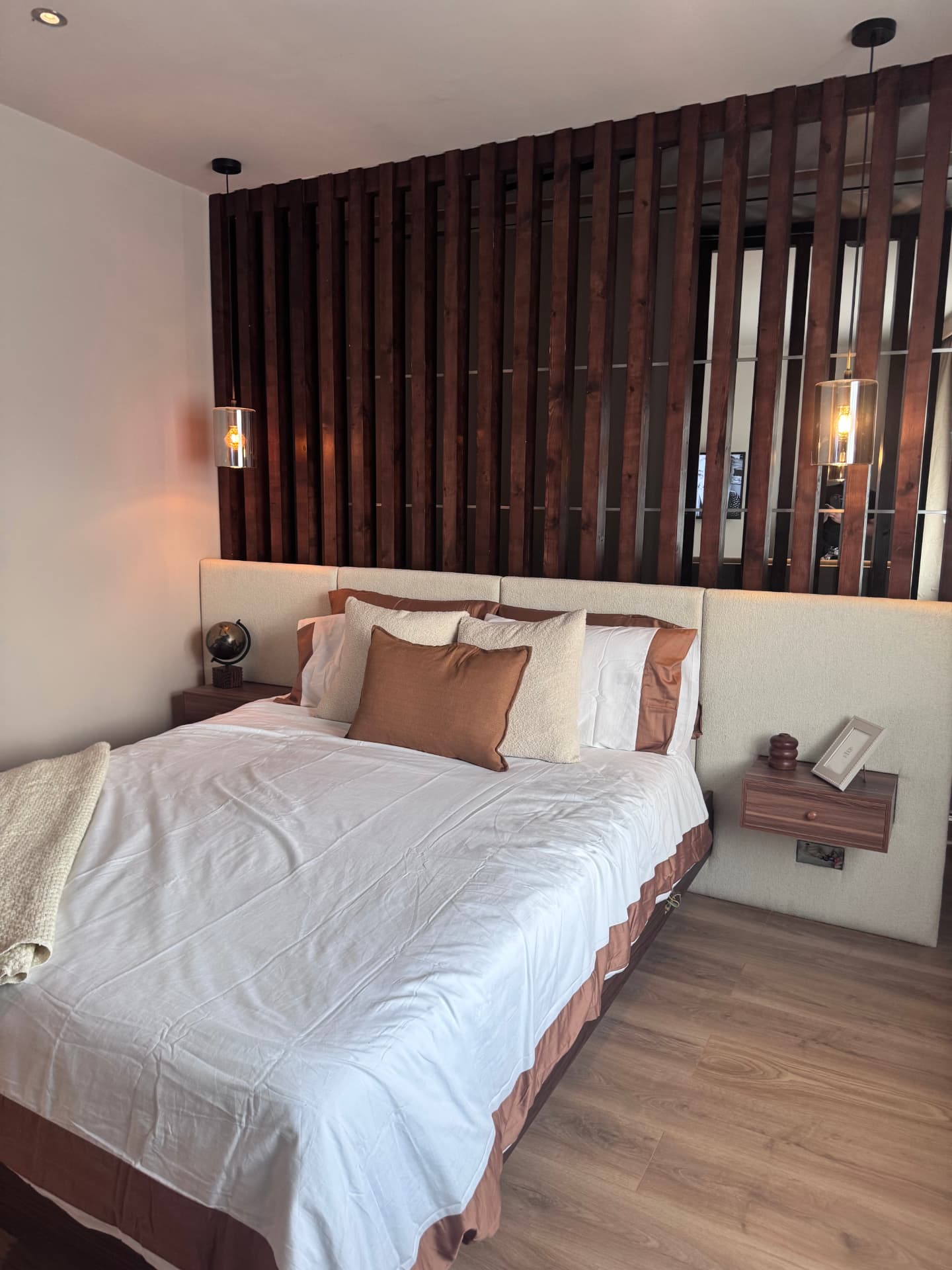 Finished hotel-style bedroom with walnut floating bed and upholstered headboard