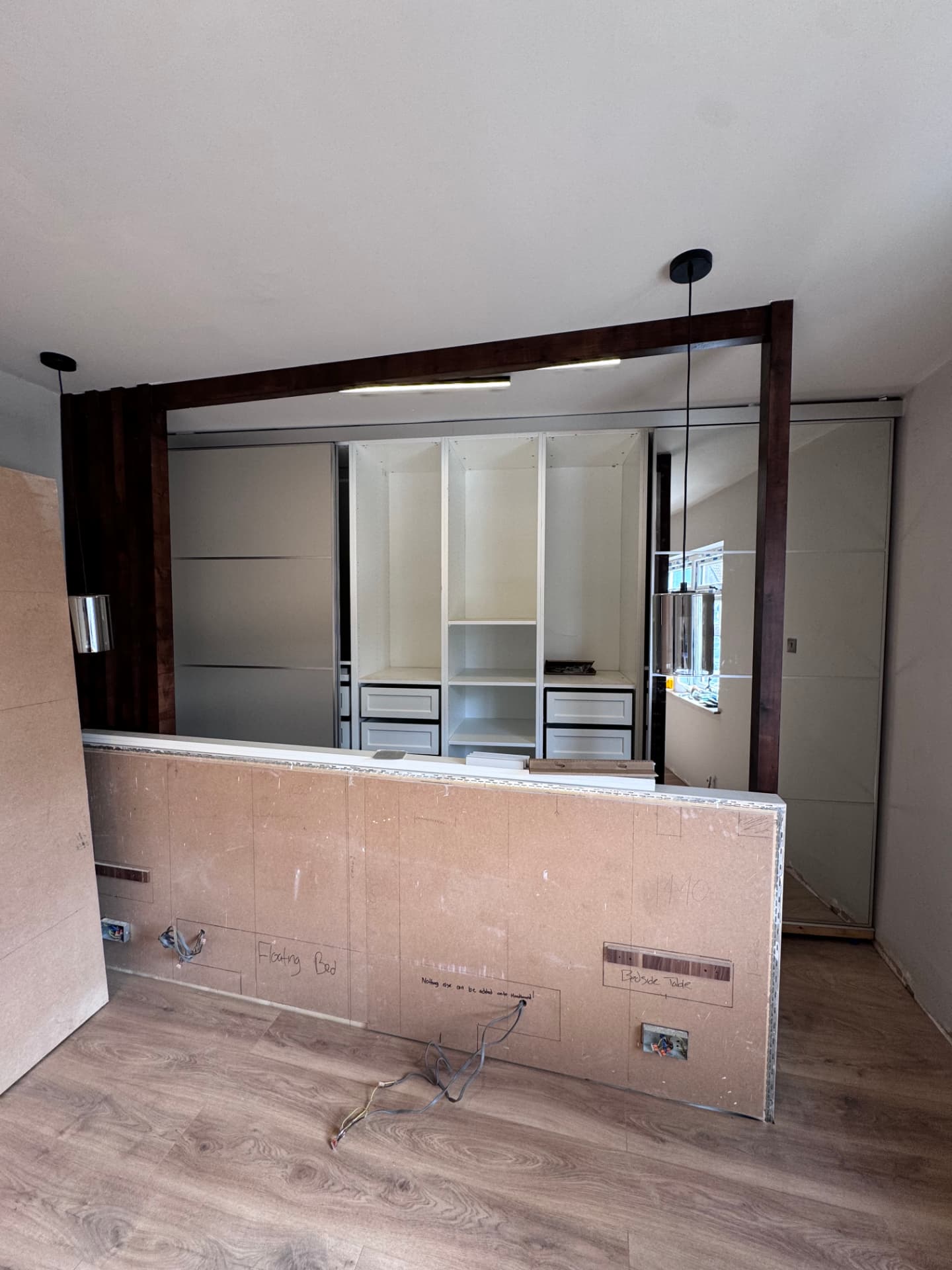 Walnut slatted feature frame and mirrored wardrobes installed