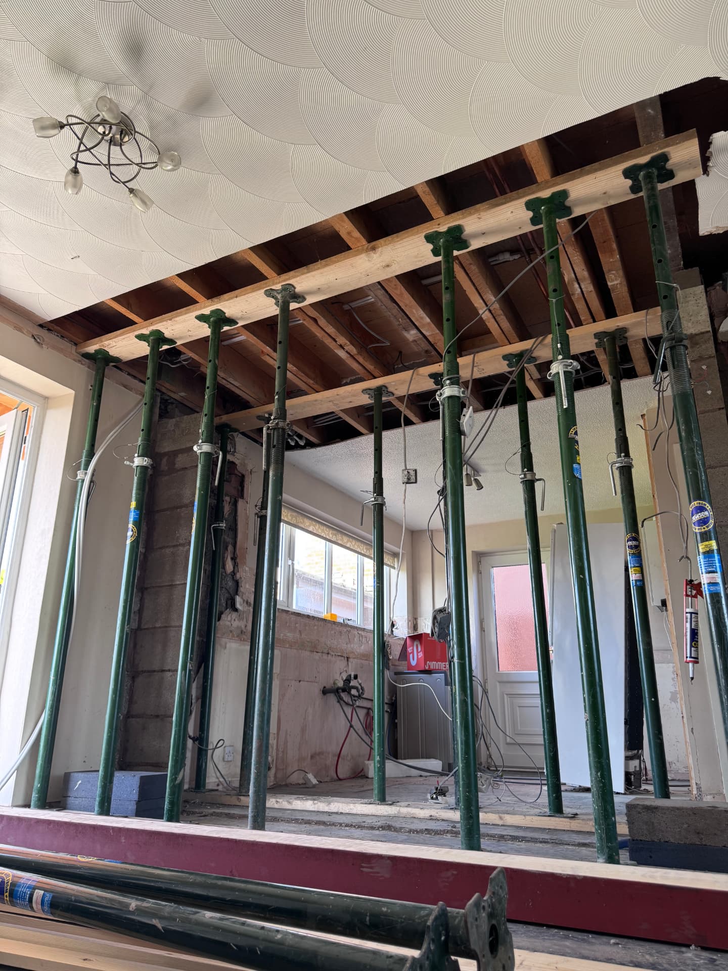 Full row of acrow props and needles supporting the joists before the steel