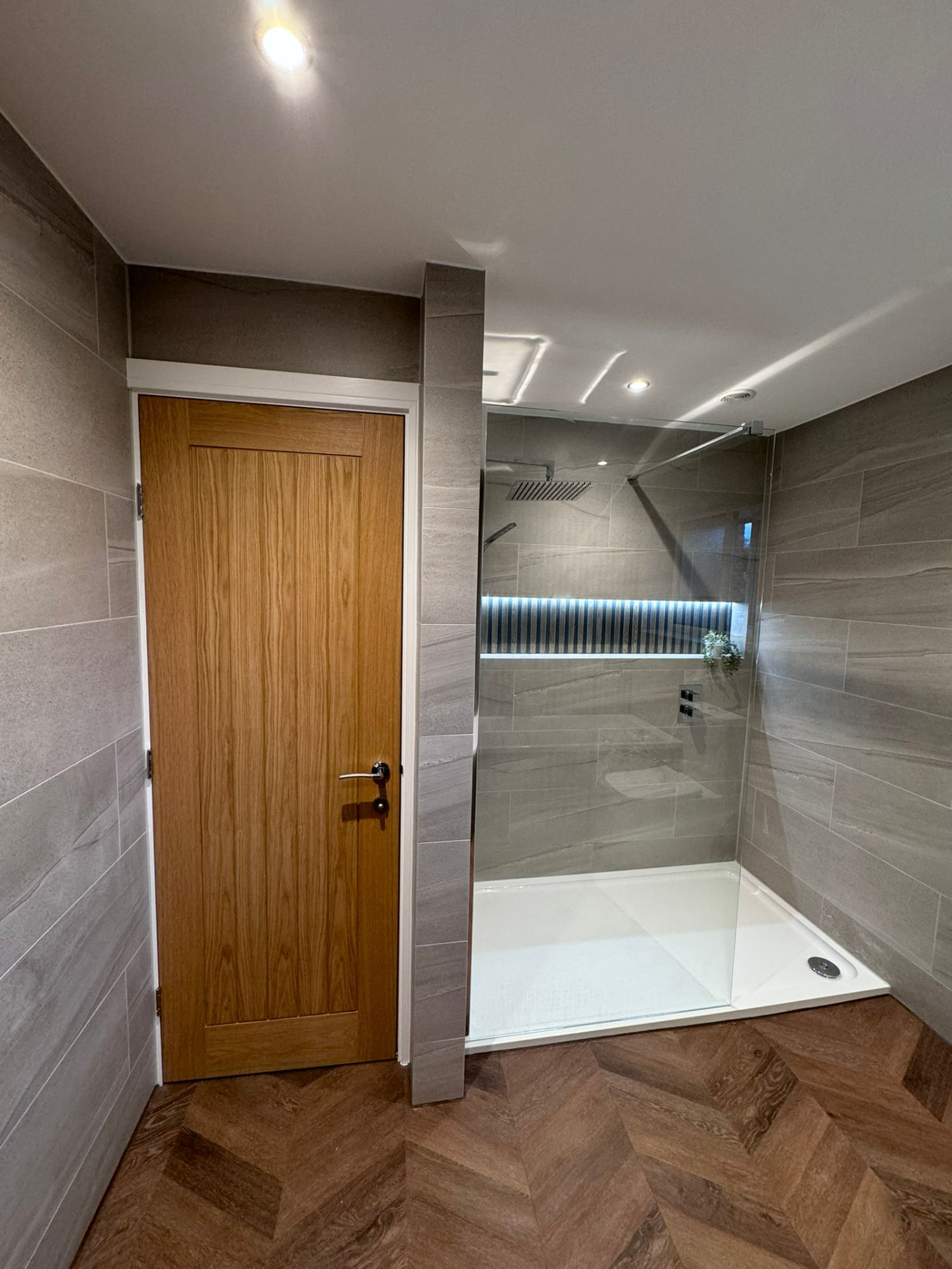 Walk-in shower with lit niche, oak door and herringbone flooring