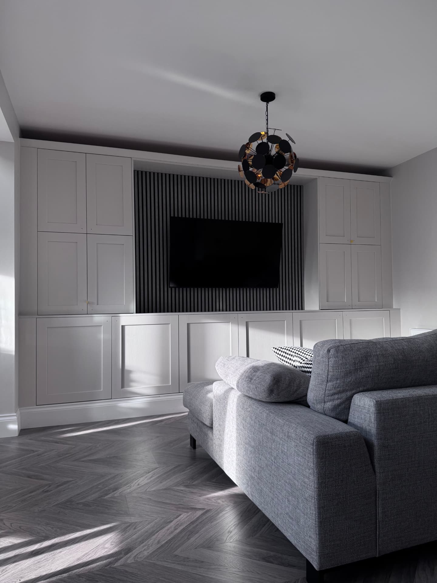 Media wall with full-height storage cupboards and slatted TV panel