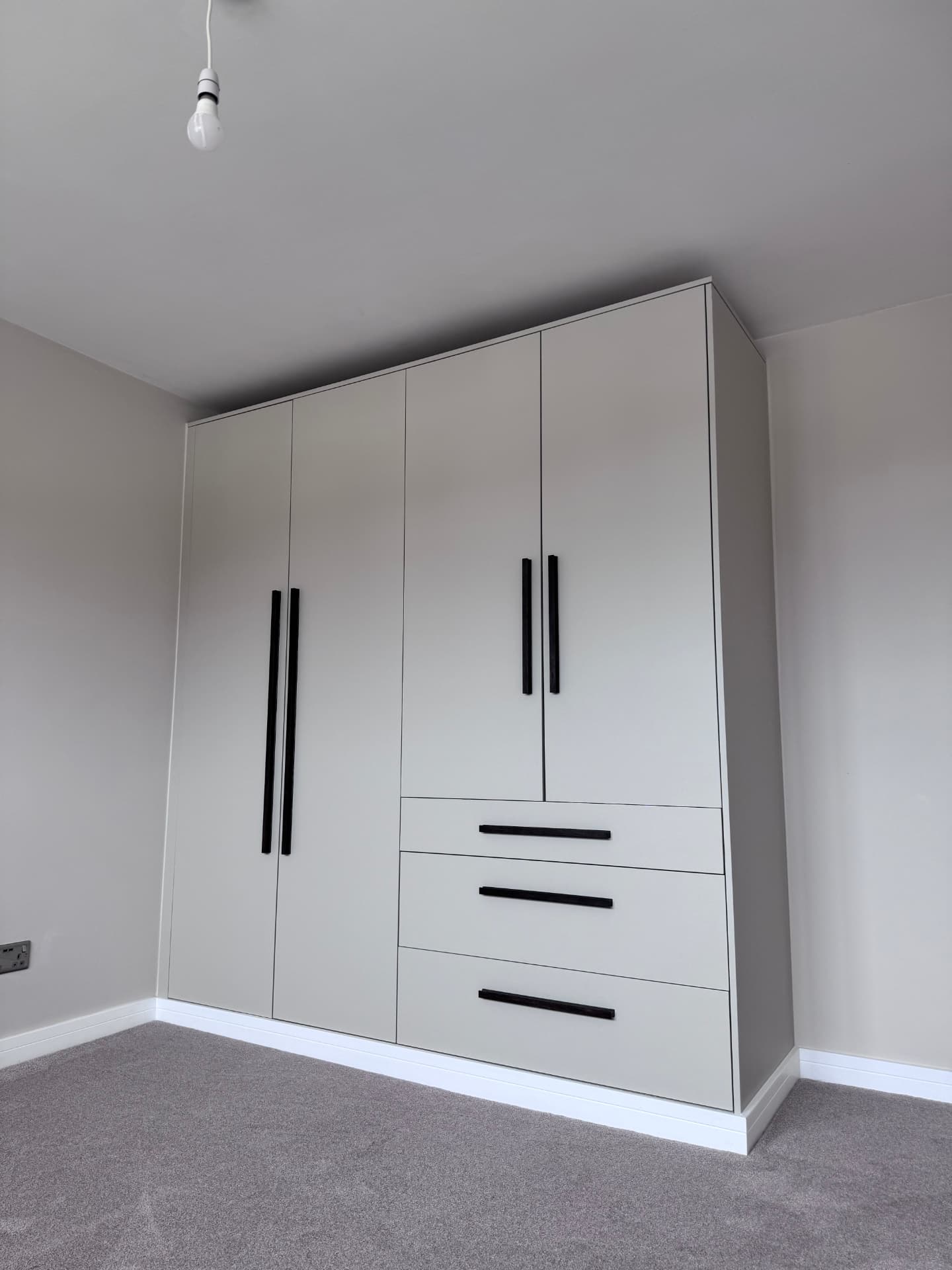 Finished fitted wardrobes with black bar handles and drawer bank
